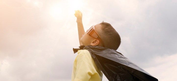 niño mira sol con capa superman