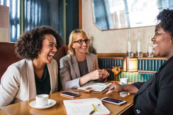 three woman sitting smiling inside room